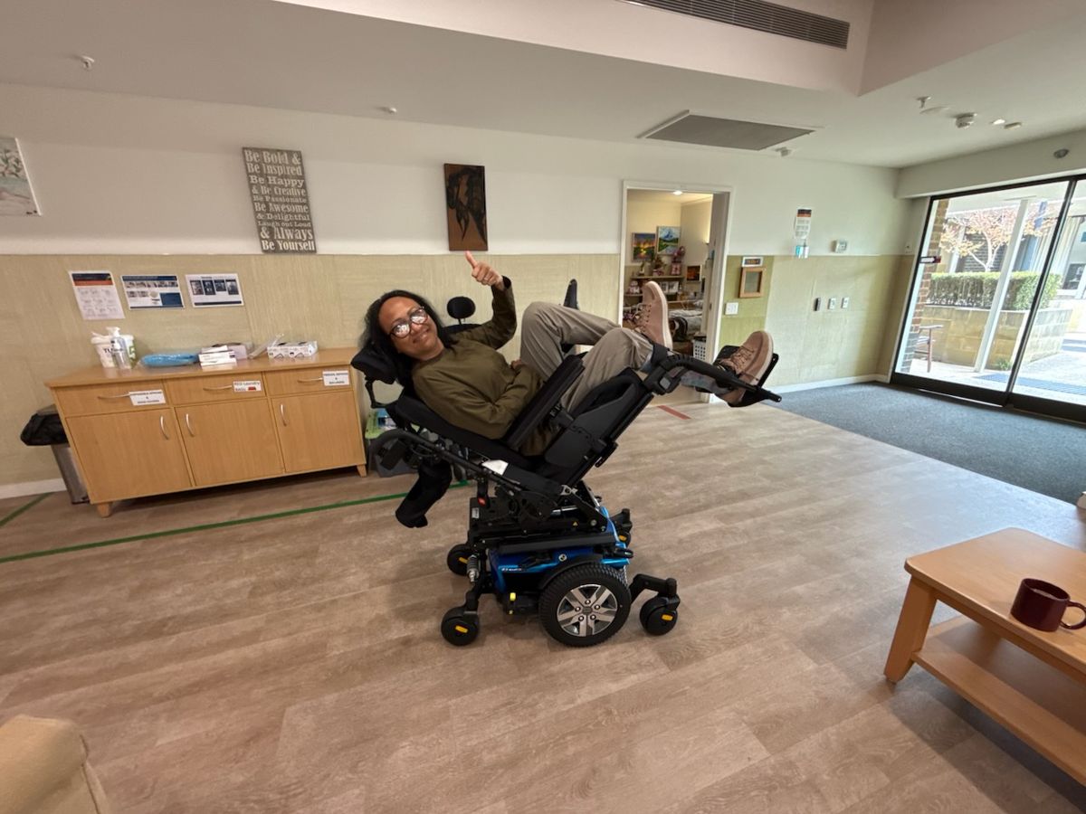 Smiling person giving a thumbs up in their brand-new blue power wheelchair